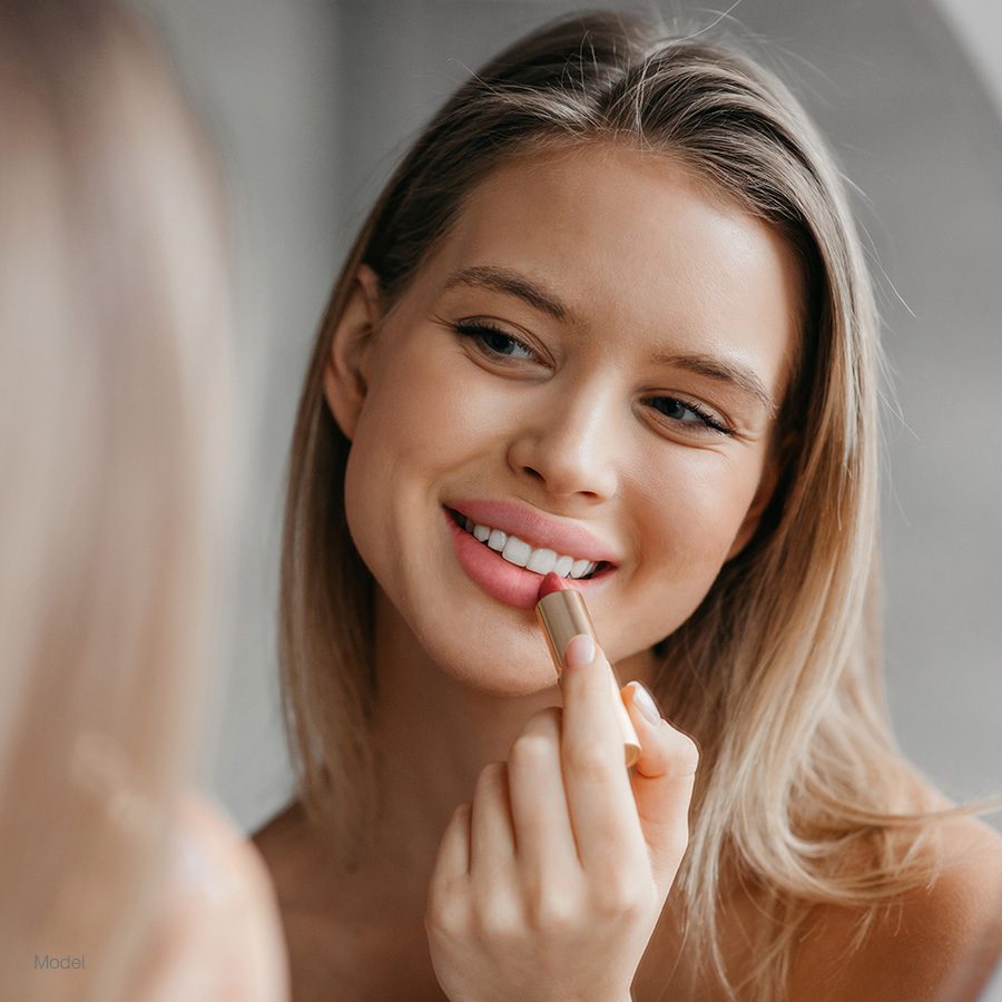 Woman putting on lip stick